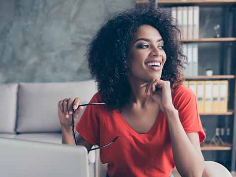 Woman with curly hair sitting at a desk Woman with curly hair sitting at a desk - https://cantianiagency.com/